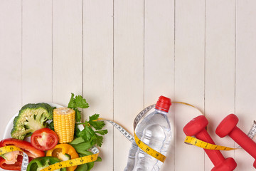 Bell pepper with measuring tape, dumbbells and bottle of water, isolated on white