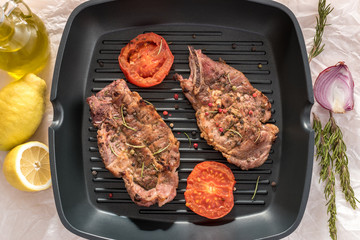 Grilled steak on grill pan with tomatoes and lemon on white background
