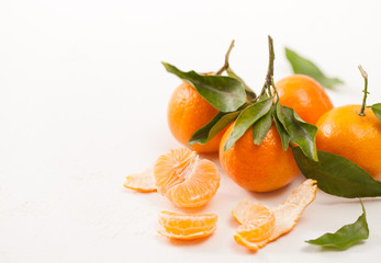 Peeled tangerines and peel with leaves on white background