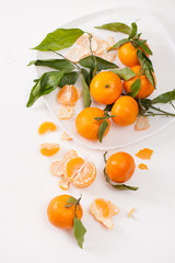 Peeled tangerines and peel with leaves on white background
