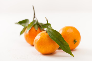 Fresh tangerines with green leaves on a white background