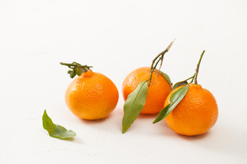 Fresh tangerines with green leaves on a white background