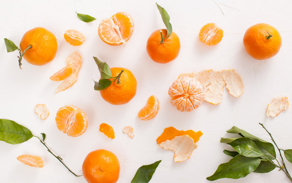 Peeled tangerines and peel with leaves on white background