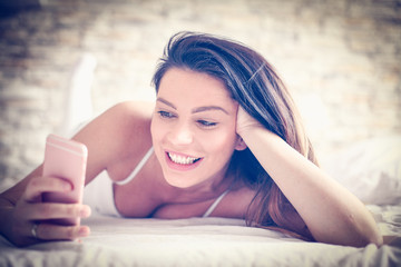 Obraz premium Woman using mobile phone in bed.