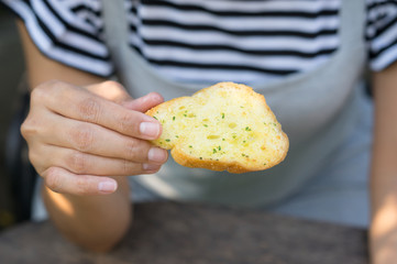 Girl eating garlic bread in hand.