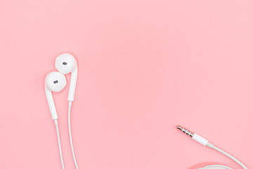 Top view Lovely Closeup of White Earphones on Pink Pastel plastic texture background. Pastel color concept, Minimal concept. Copy space. Music is my life concept. Valentine concept