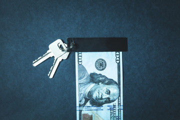 Keys and hundred dollar on a blue background.
