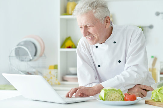elderly male chef cooking salad