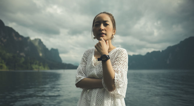 woman in white dress standing in mountain lake posing looking to camera