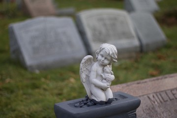 Exterior daytime shallow depth of field stock photo of cherub angel atop headstone in Mt. Hope...