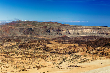Teide National Park, Tenerife, Canary Islands - colourful soil of the Montana Blanca volcanic ascent trail to the 3718 m Teide peak. The Teide astronomical observatory can be seen in the distance.
