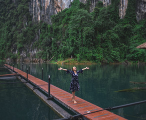 Fototapeta na wymiar Young female walking towards the freedom on a walkway wood in lake and mountain background