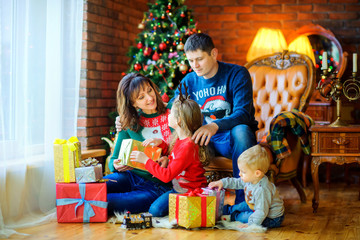 happy family in the room near the festive Christmas tree, give gifts to each other and have fun.