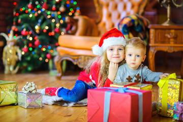 Fototapeta na wymiar sister gently hugs her little brother sitting on the floor near the gifts.