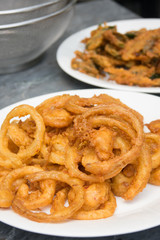 Onion ring in white dish with fried various vegetables on table