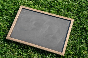 Abstract chalk blackboard with wood border frame on grass floor included copyspace ready used as background for add text or graphic