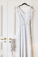 Wedding dress hanging on a hanger in a hotel room on the door