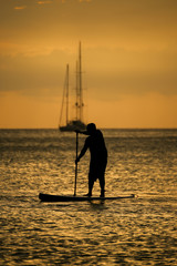 Silhouette of man with paddle and surf board sunset moment