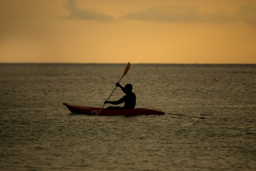Naklejka premium Silhouette of man with paddle and Kayak sunset moment
