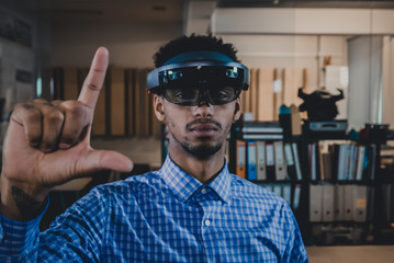 Portrait of young African American black male professional using augmented reality holographic hololens in modern office