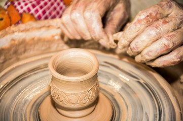 Fototapeta na wymiar clay bowl on pottery wheel and potter hands close up