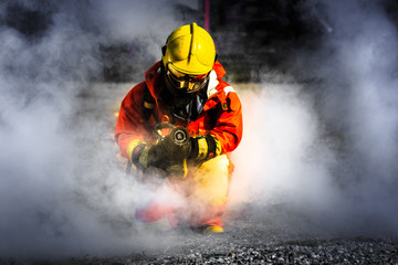 Firefighter in fire fighting operation, Firefighter using extinguisher and water from hose for fire...
