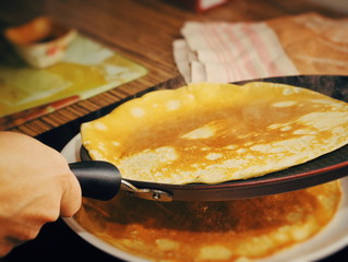 The woman cooks pancakes, pancakes in a frying pan, women's hands