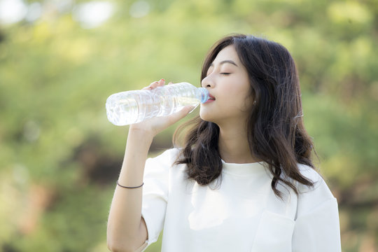 Attractive Asian Woman drinking water at garden. Woman with health care concept.