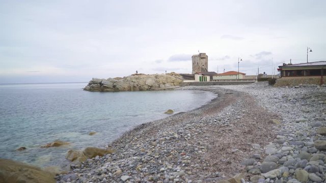 Stone shore on and an ancient tower on island in the fall on cloudy day