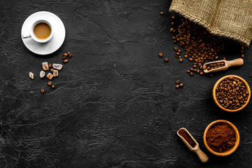Coffee concept. Roasted beans, ground coffee, cup of espresso and sugar on black background top...