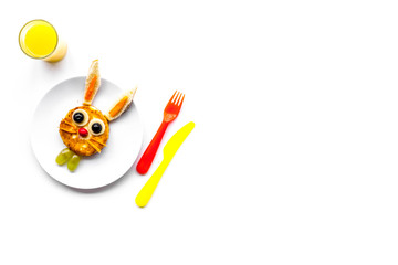 Funny breakfast for children. Meal with cheesecake in shape of hare. White background top view copyspace