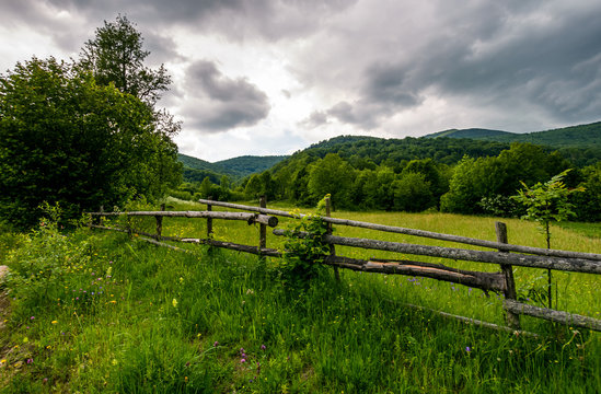 wooden fence on a rural meadow in mountains. lovely agriculture scenery on a cloudy summer day