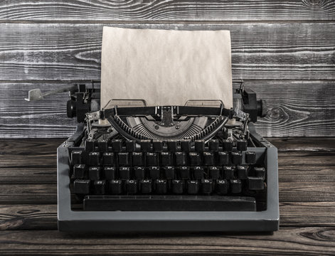 Vintage typewriter with paper sheet on wooden background. Space for your text, layout and simulation. Old