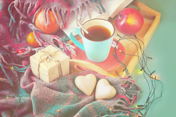 Cup of tea, festive garland, gift and hearts on the vintage background plaid, toned. Valentine's day concept.