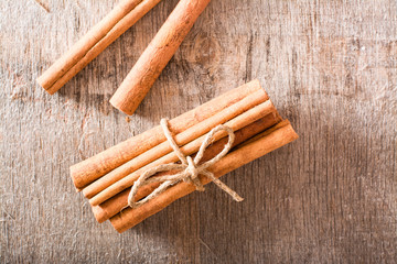 Cinnamon sticks, tied with a rope, lie on a wooden table. Fresh spice. Top view