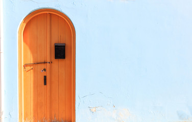 Brown wooden door on light blue background. Closeup view, copyspace.