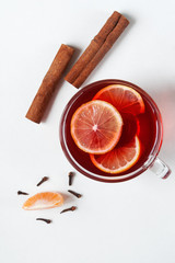 Winter drink. Mulled red wine with cinnamon sticks, tangerine and cloves on a white background. Flat lay. 