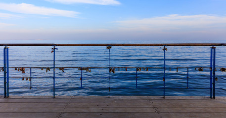 Obraz premium Rusty padlocks closed on peeled railing proving love. Close up view, blue sky and sea background.