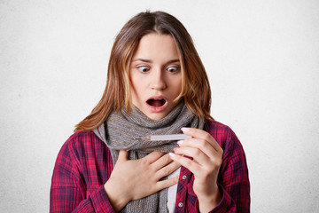 Shocked stupefied female stares at termometer, has very high temperature, caught cold, needs to be...