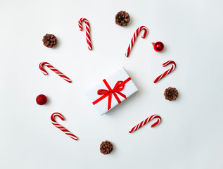 Joyful christmas background. Beautiful present box, traditional candy cane lollipops, cones and tree ball toys. Preparing for winter holidays concept, top view