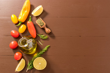 Naklejka na ściany i meble Olive oil, tomato, lemon, pepper and herbs on dark wooden table. Top view.