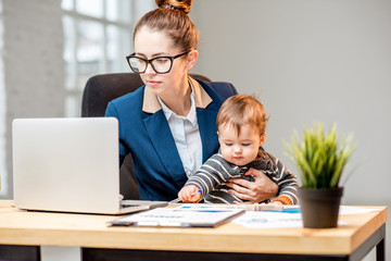 Young multitasking businessmam dressed in the suit working with laptop and documents sitting with...