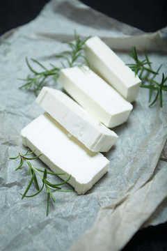 Sliced feta cheese with rosemary on the table.