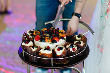 Cake and cupcakes in the center with a large tray with wheels. The man cut the cake.