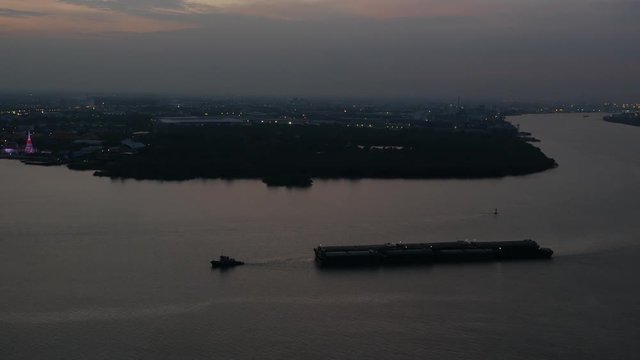 Aerial view of tugboat and Cargo transport ship passing in Chao Phraya river at sundawn.  Bangkok, Thailand