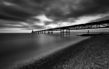 Seascape with jetty during a dramatic cloudy sunset