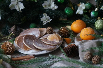 Wonderful oatmeal pancakes with tangerine jam on gray-green background with pine cones, cinnamon and alstromeria