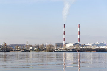 Two smoking chimneys on the river bank