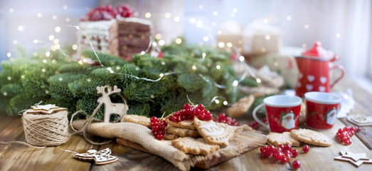 two small cups of coffee and a coffee pot, a cake with berries and cookies, gifts, near a Christmas tree on a village table near the window