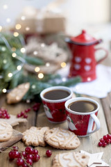 two small cups of coffee and a coffee pot, berries and cookies, gifts, near a Christmas tree on a village table
